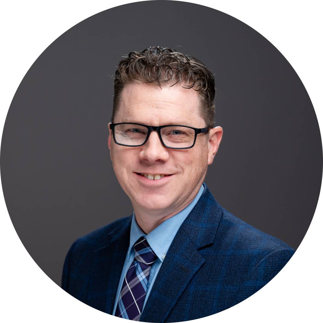 Stephen Labue smiling for his professional GVSU photo, wearing glasses and a navy suit.